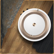 Top view of white and gold robotic vacuum cleaner on mixed hardwood and carpet floor