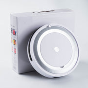 White robotic vacuum cleaner with silver ring design leaning against a white product box