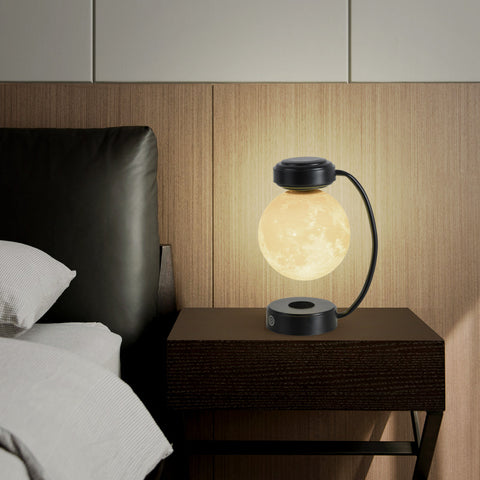 Levitating moon lamp glowing warm on bedside table next to black leather headboard