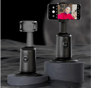 Black 360-degree AI face tracking phone holders on dark pedestals, one holding a phone with a face detected