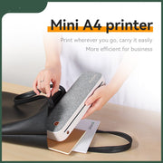 Person placing a compact grey Mini A4 printer into a black handbag on a wooden table
