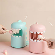 Pink and blue dinosaur-shaped silicone finger guards for holding small objects on a beige background