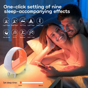 Couple smiling in bed with a modern circular atmosphere lamp and Bluetooth speaker on nightstand
