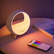 Modern circular atmosphere lamp with digital clock on table, smartphone with color control app, and book