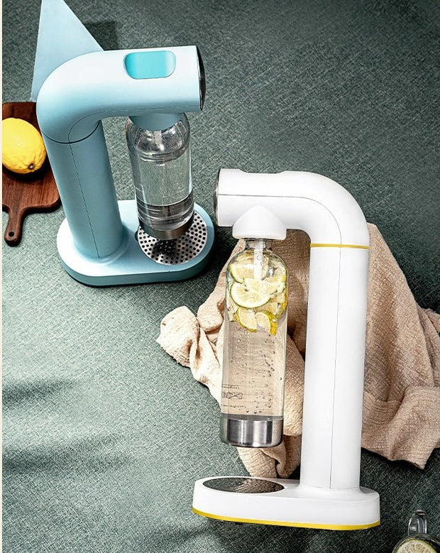 Two modern carbonated water makers with clear bottles, one with lemon and cucumber slices, on green textured surface