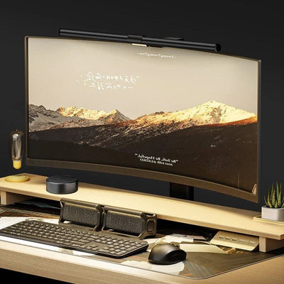 Curved computer monitor with eye protection lamp, speakers, keyboard, mouse, and wooden desk setup