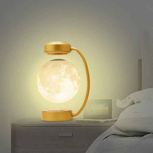 Modern gold desk lamp with levitating glowing moon light on bedside table in bedroom