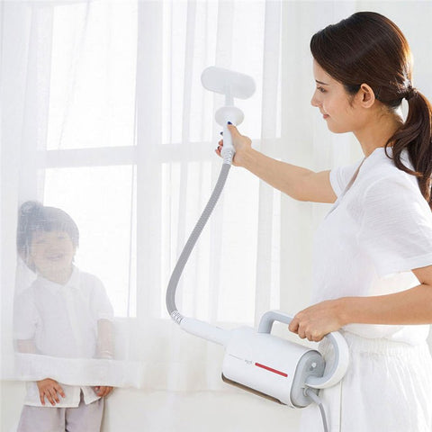 Woman using white Deerma handheld steam cleaner with brush on window curtain next to smiling child