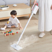 White steam cleaner being used on wooden floor near child playing with blocks in modern living room
