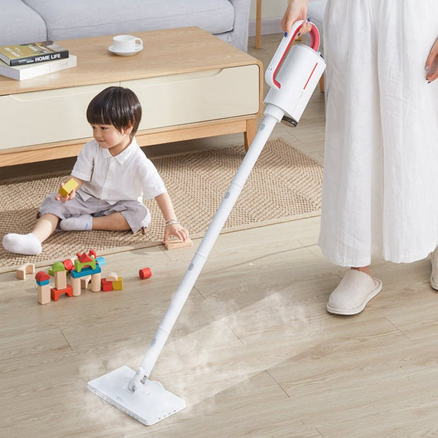 White steam cleaner being used on wooden floor near child playing with blocks in modern living room