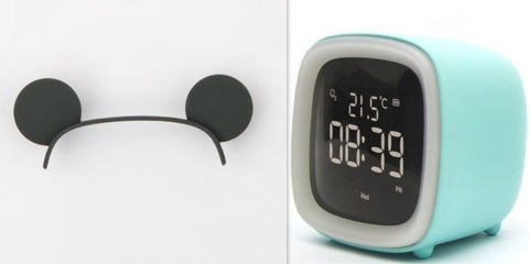 Black cat ear headband and digital desk clock thermometer with teal casing showing time 08:39