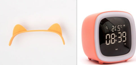 Orange digital desk clock with thermostat beside detachable orange cat ear headband on white background
