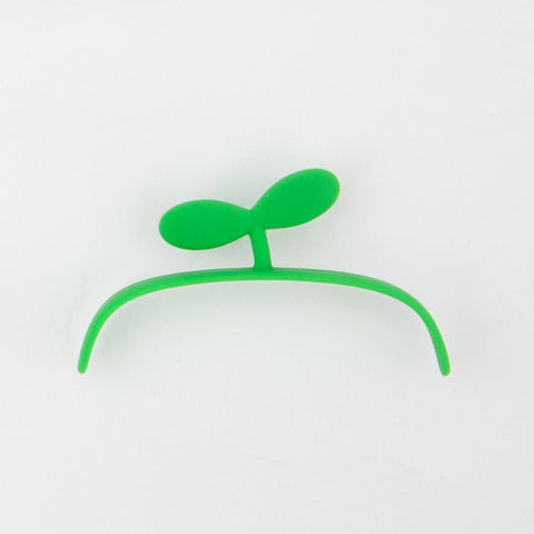 Green silicone hair clip shaped like a small plant sprout on white background