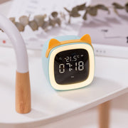 Digital desk clock with thermostat display and orange cat ears on white table