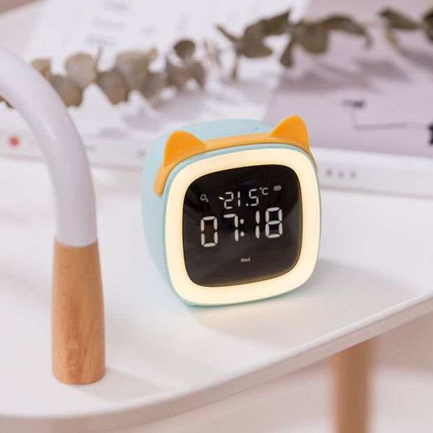 Digital desk clock with thermostat display and orange cat ears on white table