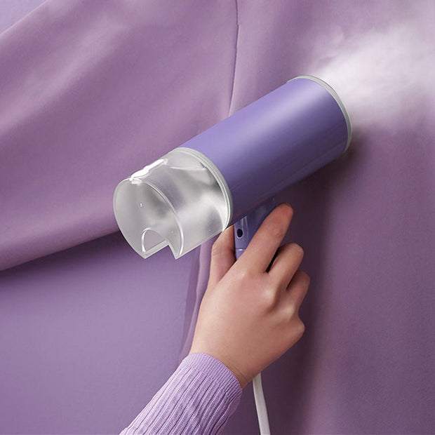 Handheld purple garment steamer removing wrinkles from matching purple fabric