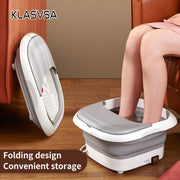 Person using foldable white electric foot bath massager on wooden floor near brown sofa