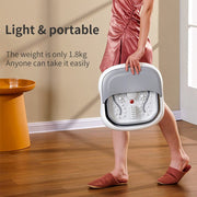 Person in pink dress holding a light portable foot spa massager in a room with wooden floor and orange side table