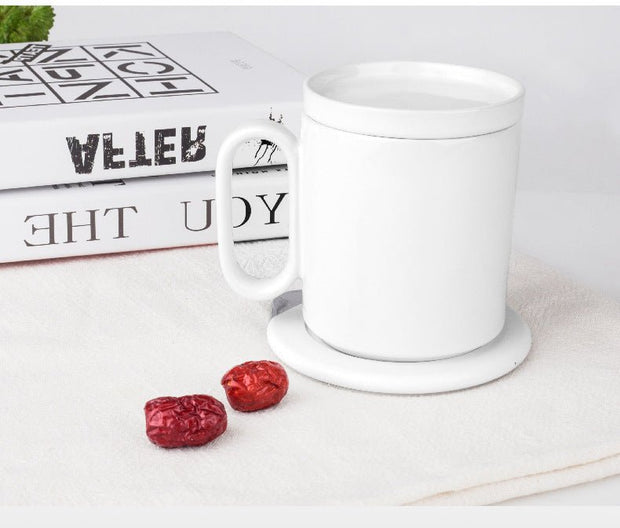 White ceramic mug on an induction heating coaster with two red dried dates and stacked books in background