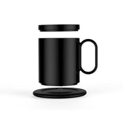 Black induction warming cup with lid and wireless heating coaster on white background