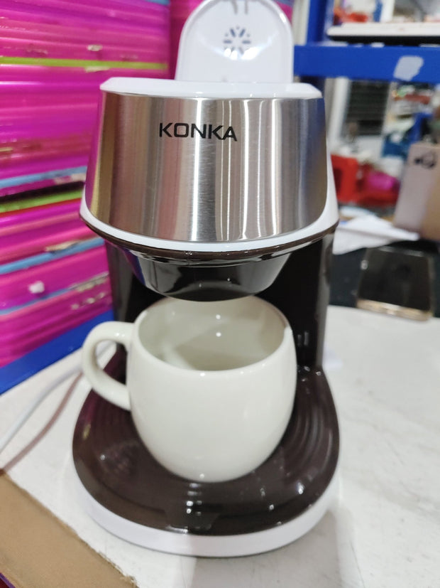 Konka compact coffee maker with a white ceramic cup on a countertop, colorful background