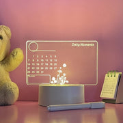 Light-up acrylic message board calendar with daily moments text, flowers design, marker, teddy bear, and desk calendar
