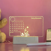 Light message writing board calendar glowing on desk with flowers design, teddy bear, and pen