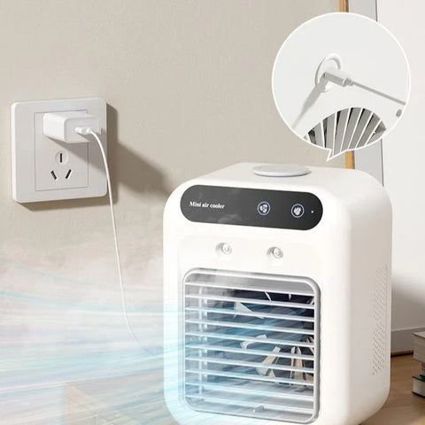 White mini air cooler plugged into wall outlet blowing cool air on wooden surface