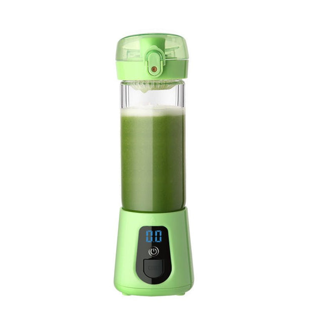 Green portable blender with digital display and green juice inside on white background