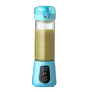 Compact blue portable blender with digital display and green smoothie inside on white background