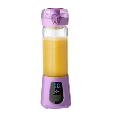 Purple portable electric juicer filled with fresh orange juice on white background