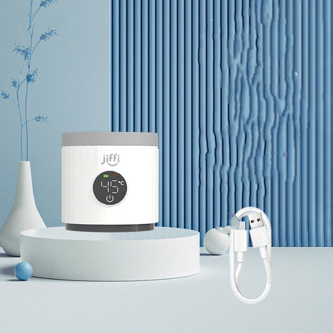 White Jiffi portable milk temperature regulator displaying 45°C with USB charging cable on blue decorative background