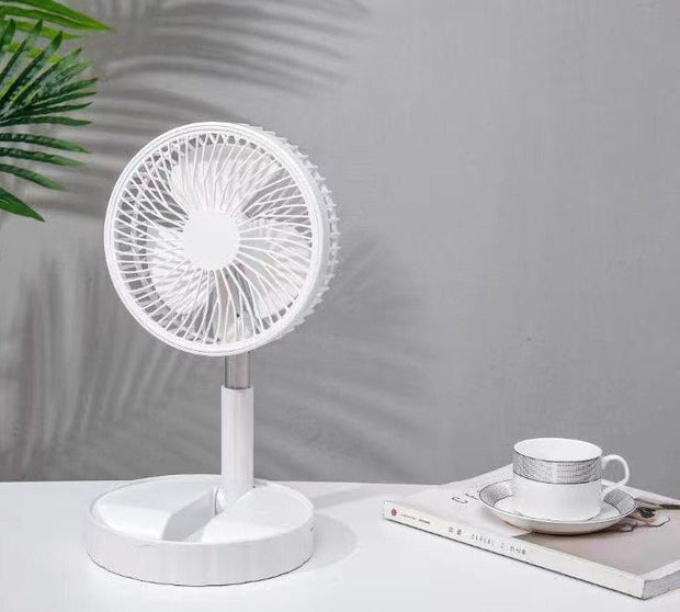 White portable desktop fan on a table with a teacup and saucer on a book, modern minimalist setting