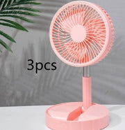 Pink portable telescopic folding fan on a white surface with a plant shadow background