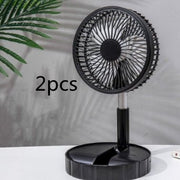 Black portable telescopic folding fan on desk with green plant in background