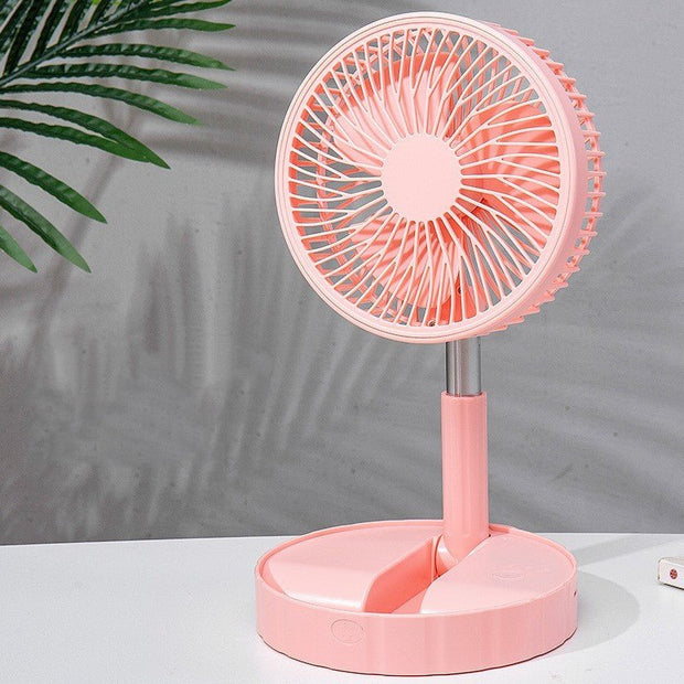 pink portable telescopic folding desk fan on white surface with leafy plant shadow
