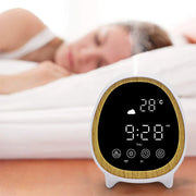 Smart aroma diffuser with digital clock, temperature, and settings display on wooden table near sleeping woman