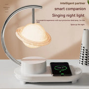 Modern smart LED lamp shaped like Saturn with wireless phone charging on white desk