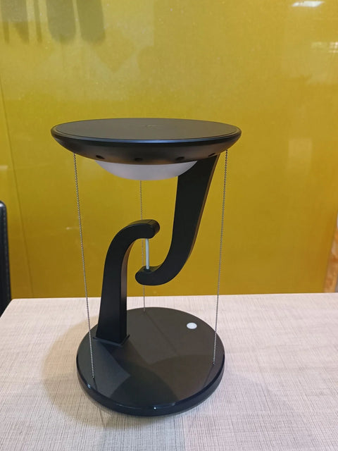 sleek black wireless floating charger with round base and yellow background